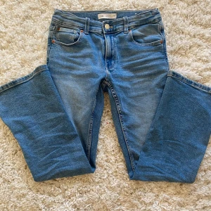 Blå bootcut jeans från Zara - Snygga och jättesköna blå jeans från Zara i klassisk bootcut-modell. Jeansen har en klassisk femficksdesign och passar perfekt till höst och vinter med en stickad tröja . Perfekta för dig som gillar en tidlös look med lite utsvängda ben.
