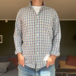 Rutig skjorta från Ralph Lauren S - Snygg rutig skjorta från Ralph Lauren i storlek S. Skjortan har pastelliga toner i blått, lila, grönt och orange, klassisk krage och knäppning framtill. Tillverkad i mjuk bomull och har långa ärmar. Perfekt för en chill och stilren look. Hör av er vid frågor!👍