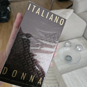 Armaf Italiano Donna parfym 100ml - Italiansk-inspirerad parfym för kvinnor från Armaf, Italiano Donna. Flaskan rymmer 100 ml och kommer i en lyxig mörkbrun kartong med guldiga detaljer och mönster. Eau de Parfum med elegant och modern design, perfekt för dig som gillar exklusiva dofter.