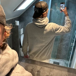 Grå hoodie från ONSF med brodyr - Säljer en grå hoodie från ONSF med liten broderad logga på bröstet och diskret tryck på ryggen. Tröjan har huva med snörning och en stor magficka. Perfekt för chill dagar och enkel att matcha med det mesta.