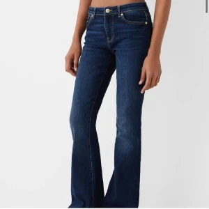 Mörkblå bootcut jeans - Snygga mörkblå jeans med bootcut passform och klassiska gula sömmar. Jeansen har normal midja och fem fickor, perfekta för en avslappnad men trendig look. Tillverkade i mjukt denimtyg som sitter skönt hela dagen.