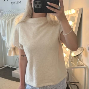 Beige stickad kortärmad tröja - Superfin beige stickad tröja med korta ärmar och rak passform. Mjuk och skön, perfekt för lager-på-lager eller som den är. Enkel och stilren design som passar till det mesta.
