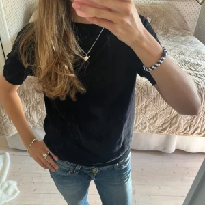 Stickad t-shirt från Lindex - En svart t-shirt från Lindex i storlek XS. T-shirten har korta ärmar, rund halsringning och är gjord i ett mjukt, stickat material som känns skönt mot huden. Enkel och stilren modell som passar till jeans eller kjol. Öppen för prisförslag