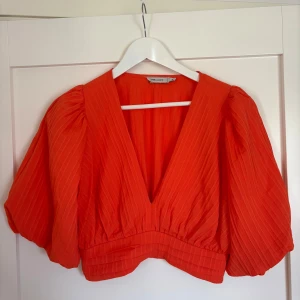 Orange blus - Snygg orange blus från Vera & Lucy med puffiga korta ärmar och djup v-ringning. Aldrig använd