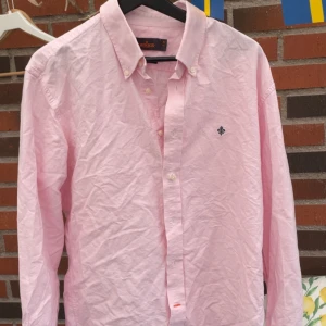 Ljusrosa skjorta från Morris,  - Snygg ljusrosa skjorta från Morris. Plagget har skador på änden på armen vilket säkert går att sy ihop. Plagget kan dessutom användas under en tröja utan att skadorna påverkar eller syns. 