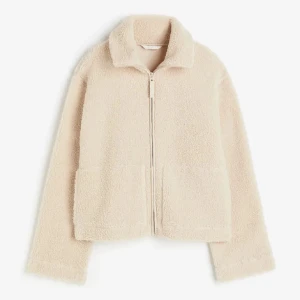 SÖKER!!! Beige teddyjacka med dragkedja - Mysig beige teddyjacka med krage och hel dragkedja framtill. Jackan har två stora fickor och är tillverkad i fluffigt teddy-material som ger en chill och trendig vibe. Perfekt för lager-på-lager och passar till både jeans och mjukisbyxor.
