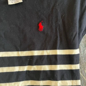 Randig tshirt från Polo Ralph Lauren - Snygg tshirt från Polo Ralph Lauren i marinblått med vita horisontella ränder och klassisk röd broderad logga på bröstet. Tillverkad i mjuk bomull som känns skön mot huden.