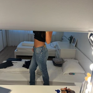  ljusblå jeans straight fit - Säljer ett par jeans i ljusblå tvätt. Jeansen har låg midja, raka ben och en avslappnad passform. De är tillverkade i bomull och har slitna detaljer framtill för en cool, vintage vibe. Perfekta för dig som gillar en tidlös och chill stil.