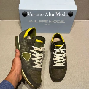 Philippe Model sneakers i olivgrönt - Snygga sneakers från Philippe Model i olivgrönt med gula detaljer och vita snören. Ovandelen är en mix av mocka och textil, med en ikonisk sköld på sidan. Skorna har platt sula och rund tå, perfekt för dig som gillar stilrena men unika sneakers. Man får såklart allt Og med🙌