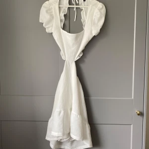 Vit klänning med volang - Vit klänning med öppen rygg. I storlek 38, men passar mig som har 36. I nyskick!