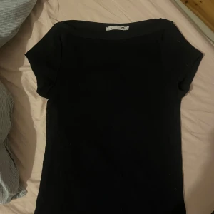 Svart kortärmad topp från 157 - Enkel och stilren svart topp från 157 med korta ärmar och rund halsringning. Perfekt att matcha med jeans eller kjol för en clean look. Mjuk och skön, passar dig som gillar basic plagg med snygg passform.