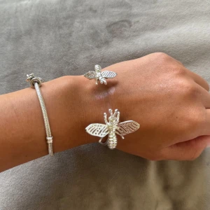 Ioaku armband  - Unikt armband i silverfärgad metall med två detaljerade bin på varje ände. Armbandet är stelt och öppet, vilket gör det lätt att ta på och av.  Knappt använd. 