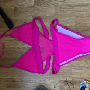 rave neon outfit - Snygg rosa bikini med klassisk trekantsöverdel och matchande trosor. Bikinin har tunna band som knyts i nacken och ryggen för en justerbar passform. 