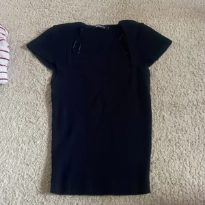 Svart ribbad kortklänning Gina Tricot - Svart ribbad kortklänning från Gina Tricot med korta ärmar och rund hals. Klänningen har en figurnära passform och är tillverkad i ett stretchigt material som sitter snyggt på kroppen. Perfekt för dig som gillar en enkel men stilren look.