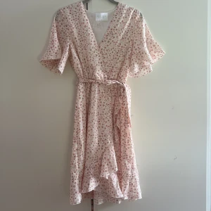 Blommig klänning - Rosa blommig klänning i omlott stil från Sisters Point! Den har lite volanger vid kjol och ärmar