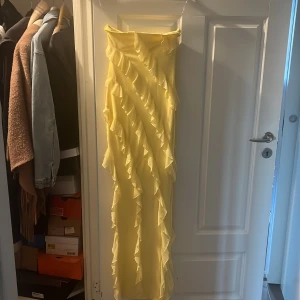 Gul långklänning med volanger Oh Polly - Säljer en superfin gul långklänning från Oh Polly. Klänningen har axelbandslös design och är täckt av diagonala volanger som ger en riktigt cool och unik look. Perfekt för dig som vill sticka ut och älskar färg! Passar till sommarens alla tillfällen. Köpt för 1000kr har endast använts en gång.