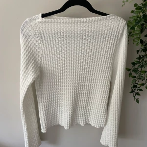 Vit långärmad ribbad tröja - Säljer en vit långärmad tröja med ribbad struktur och vågigt mönster. Tröjan har en enkel och clean look med hög hals. Perfekt att styla med jeans eller kjol. 