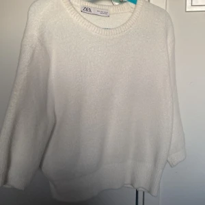 Vit tröja från Zara - Säljer en mysig vit tröja från Zara med rund halsringning och trekvartsärmar. Perfekt för en stilren och bekväm look. Passar bra till både jeans och kjol.