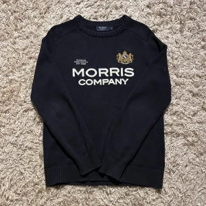 Svart/ mörkblå finstickad tröja från Morris M - Snygg svart/ mörkblå tröja från Morris med broderad logga och text på framsidan. Tillverkad/finstickad i 100% bomull för en bekväm känsla. Perfekt för en stilren look. Ribbade muddar vid ärmslut och nederkant. Storlek M, sitter som M men mått skickas såklart vid osäkerhet. Postas antigen samma dag som köp eller dagen därpå🙌💯
