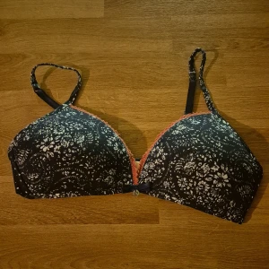Blå blommig mjuk bh från Esprit storlek 75A, ny - Säljer en snygg blåmönstras bh från Esprit med vita blommor och spetsdetaljer i diskret rosa. Bh:n har justerbara axelband och en bekväm passform. Den är bygelfri och Plicks AI tycker den är "perfekt för att ge en touch av stil till vardagen". Aldrig använd såklart, men på denna finns inte etiketten kvar. Nypris 199 kronor. Skickar helst med Instabox. Kan också hämtas i Malmö, vid Hansa.