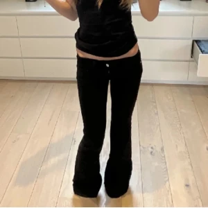 Svarta bootcut jeans - Snygga svarta bootcut jeans med låg midja. Perfekta för en avslappnad stil. De har en klassisk femficksdesign och stängs med dragkedja och knapp.