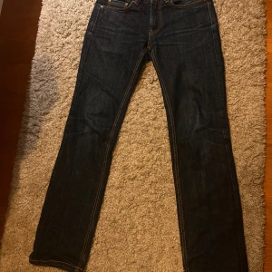 Mörkblå jeans från Acne Jeans - Snygga mörkblå jeans från Acne Jeans med klassisk femficksdesign och orange sömmar. De har en rak passform och är perfekta för en stilren look. Midjan är normalhög och de är tillverkade i slitstarkt denim. W30 L32