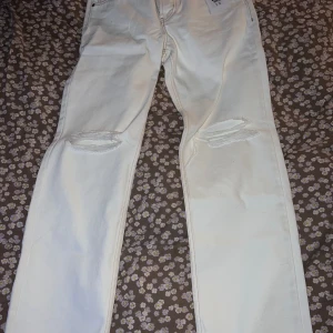 Vita jeansbyxor från Junkyard - Snygga vita jeansbyxor från Junkyard med slitna detaljer på knäna. Helt oanvända med prislappen kvar.      Nypris 499:-