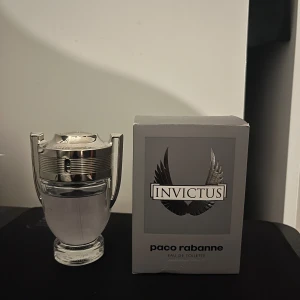 Invictus Eau de Toilette från Paco Rabanne - Säljer en flaska Invictus Eau de Toilette från Paco Rabanne. Flaskan har en unik design som liknar en trofé med silverdetaljer. Doften är fräsch och maskulin, perfekt för den självsäkra mannen. Kommer i originalförpackning.