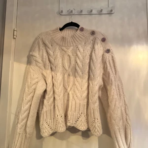 Vit stickad tröja  - Säljer en mysig vit stickad tröja från Zara med flätmönster och knappar på axeln. 