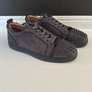 Grå sneakers från Christian Louboutin 44/45 - Säljer ett par grå sneakers från Christian Louboutin i mocka. Skorna är riktigt feta och passar perfekt nu till våren och sommarn! Kvitto finns! Andvända typ 4 gånger så dom är i ny skick. Hör av er vid frågor!