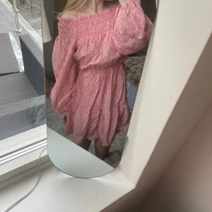 Rosa offshoulder klänning - Säljer en söt rosa offshoulder klänning med ett diskret mönster. Klänningen har långa ärmar och en smockad överdel som ger en fin passform. Stl XS men stor i stl så skulle säga S. Nu utan prislapp 