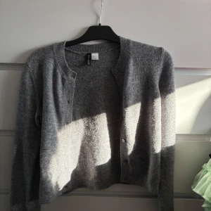 Grå kofta från H&M  - Säljer en stilren grå kofta från H&M. Koftan har en klassisk design med knappar framtill och ribbade kanter vid ärmslut och nederkant. Hör av dig vid intresse 🤗
