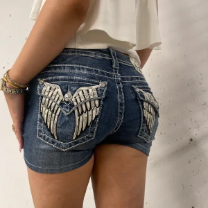 Missme jeans minishorts  - Snygga jeansshorts från Miss Me med vingbroderi på bakfickorna. De har en låg midjad passform☺️