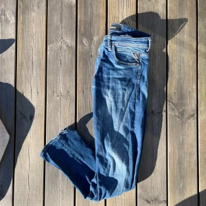 Replay Jeans - Snygga blå jeansbyxor med en klassisk femficksdesign och dragkedja. De har en lätt tvättad look med subtila slitningar som ger en trendig stil. Perfekta för en avslappnad vardagslook. Storlek 30 Straight fit fast är mer mot slim hållet!