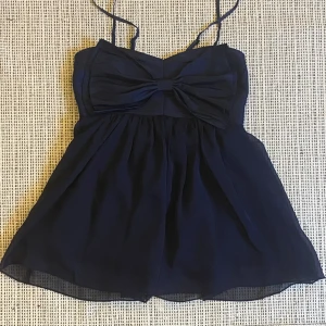 Mörkblå rosett-topp - Söt blå topp med en rosett på framsidan! Köpt second hand men har tyvärr inte kommit till användning. Bra skick. Banden är justerbara! 💙