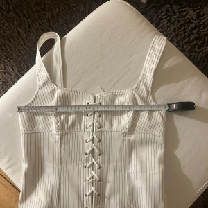 Zara korsett topp - Korsett/topp från Zara i storlek M. Vit med bruna kritstreckränder. Nytt skick, prislappen är kvar. Jag har även sytt upp banden eftersom de var väldigt väldigt långa!