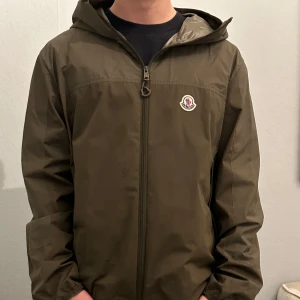 Olivgrön vindjacka från Moncler - Äkta Moncler jacka köpt på NK i Stockholm! Högt pris pga att jag ångrar köpet enormt, o vill få tillbaks så mycket som möjligt! Nypris från 12 - 14 tusen! I princip oanvänd äkta moncler, spara 5000! 