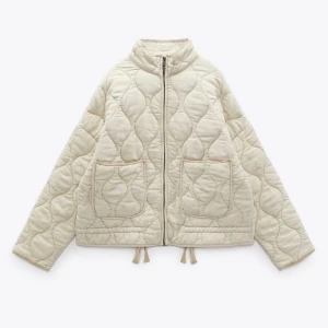 Zara Beige quiltad jacka - Använd men fint skick. Säljer en snygg beige quiltad jacka med dragkedja och två stora fickor fram. Jackan har en loose passform och är perfekt för kyligare dagar. Den quiltade designen ger en trendig look.