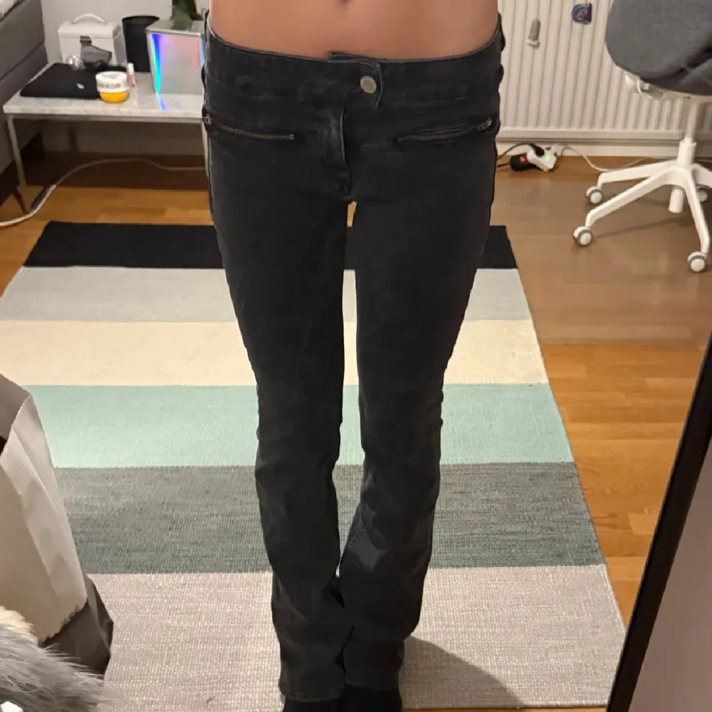 Snygga svarta bootcut jeans med låg midja och dragkedjedetaljer framtill. Perfekta för en stilren look. Passar bra till både sneakers och klackar.. Farkut & Housut.