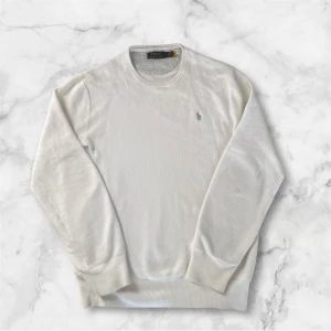 Ralph Lauren Stickad Tröja - Säljer en stilren vit tröja från Polo Ralph Lauren. Tröjan har en klassisk design med rund hals och långa ärmar. Storlek M. Priset är inte slagit i sten! Skriv om du har några frågor!