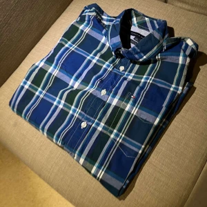 Rutig skjorta från Tommy Hilfiger - En riktigt skön rutig skjorta från Tommy hillfiger nu inför sommaren, till självklart ett dunder pris på endast 129‼️tröjan har ett litet hål som du ser på sista bilden men de är lättfixat🌟 annars dunder skick! Hör gärna av dig med frågor eller funderingar🤝