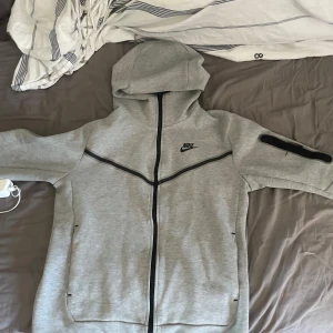Grå hoodie från Nike - Säljer nu min gråa Nike tech fleece då den är för liten på mig , väldigt fin men använd en del men det synd knappt . Fler bilder vid behov kan lösas . Pris kan diskuteras 