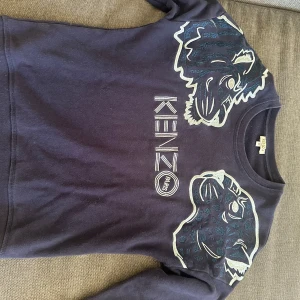 Mörkblå Kenzo sweatshirt med - Kenzo sweatshirt i mörkblått med broderade leopardhuvuden och coolt tryck och text. Fint skick, inga hål eller fläckar. Passar xs men är i barnstorlek 14 år💕