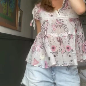 Blommig Odd Molly blus med volang - Supersöt blommig blus från Odd Molly i ljusrosa och vit med volang och knytband vid ärmarna. Luftig modell med korta ärmar och spetsdetaljer vid halsringningen. Använd en gång och i super fint skick 🩷