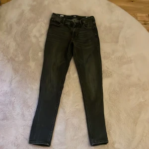 Svarta slim jeans Jack & Jones 164 - Svarta slim fit jeans från Jack & Jones, modell Glenn. Jeansen har klassisk femficksdesign, smal passform och är tillverkade i stretchigt denim för extra komfort. Snyggt slitna detaljer och diskret tvättad look. Perfekta för dig som gillar en modern och stilren vibe.