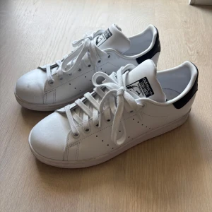 Adidas Stan Smith vita sneakers - Klassiska Adidas Stan Smith. Snygg och tidlös modell med rund tå, snörning och perforerade ränder på sidorna. Perfekta för en clean och sportig look.