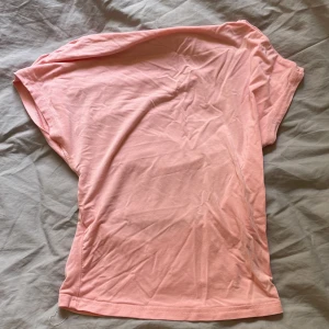 Ljusrosa kortärmad topp - Säljer en ljusrosa topp med korta ärmar och enkel, clean design. Toppen är tillverkad i mjuk bomull och har en rundad, öppen rygg som ger en chill vibe. Perfekt för dig som gillar basic men ändå vill sticka ut med färg.