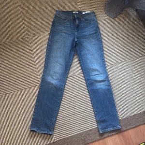 Blå straight jeans från Wrangler - Snygga blå jeans från Wrangler med klassisk femficksdesign och ikonisk W-söm på bakfickan. Modellen har rak passform och ganska hög midja, tillverkade i slitstarkt denim. Perfekta för dig som gillar tidlös stil och vill ha ett par jeans som funkar till allt. Säljer då de inte är min stil💗
