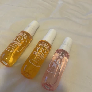 Sol de Janeiro parfymspray trio - Tre parfymsprayer från Sol de Janeiro: två Brazilian Crush Cheirosa 62 i bärnstensgul plastflaska och en Cheirosa 68 i ljusrosa plastflaska. Alla har vita spraykorkar och smidig storlek, perfekta att ta med i väskan.