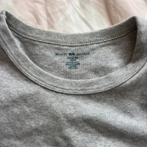 Grå t-shirt från Brandy Melville - En enkel och mjuk grå t-shirt från Brandy Melville. Modellen har rund hals och korta ärmar, perfekt för en chill och clean look. Materialet är 100% bomull och passformen är normal. Snygg att matcha med jeans eller shorts.